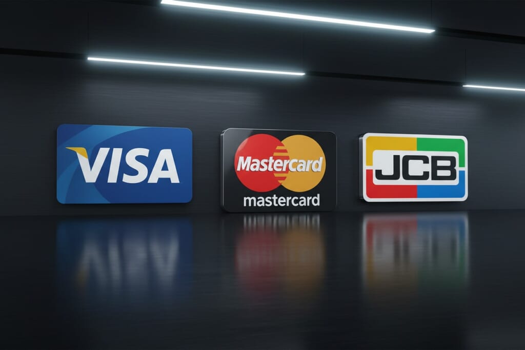 暗い壁の前に、VISA、Mastercard、JCBの3つのクレジットカードのロゴが並んでいます。